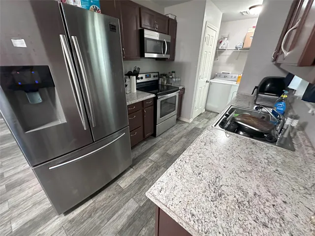 a kitchen with granite countertop a refrigerator and a sink