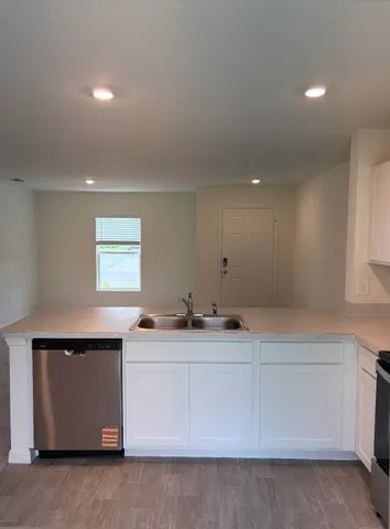 a room with a sink wooden floor and white cabinet