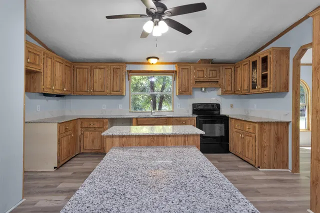 a kitchen with stainless steel appliances granite countertop a stove a sink dishwasher and a refrigerator with wooden cabinets