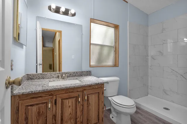 a bathroom with a granite countertop sink toilet and mirror