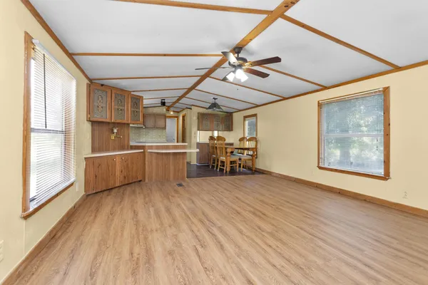 a view of a livingroom with furniture wooden floor a ceiling fan and windows
