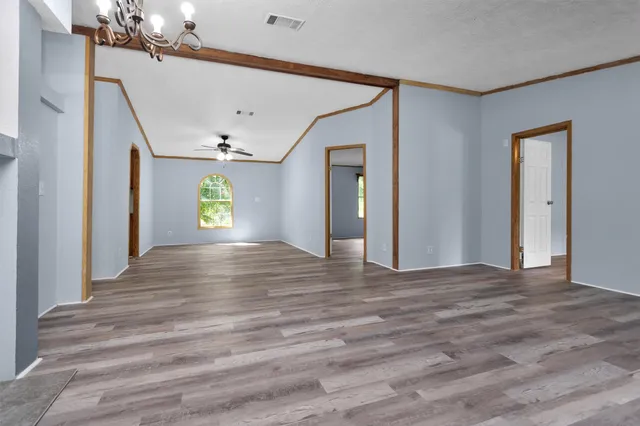 a view of an empty room with window and wooden floor