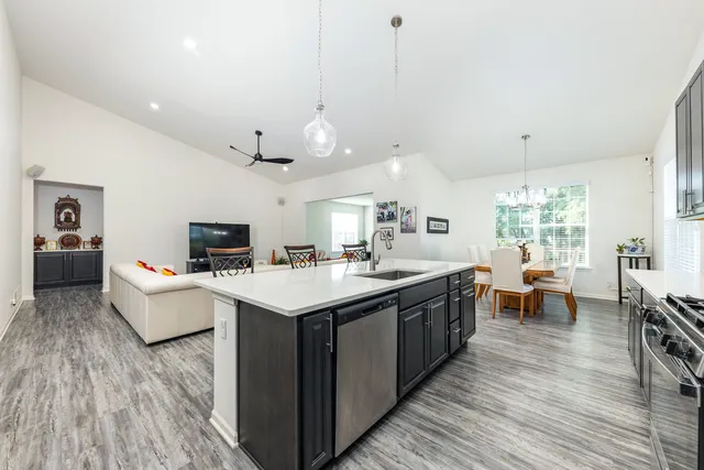 a large kitchen with kitchen island a white counter space a sink stainless steel appliances and cabinets