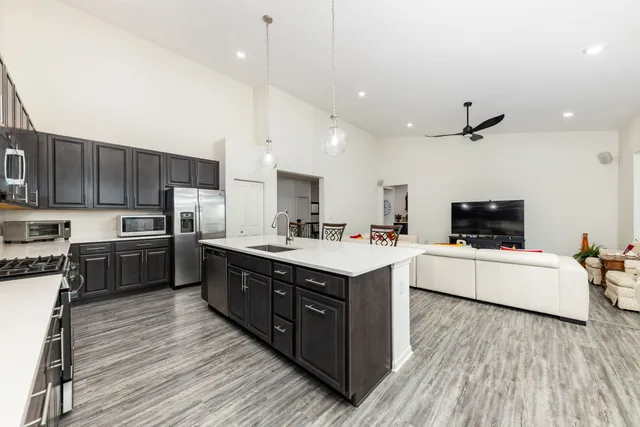a living room with stainless steel appliances kitchen island granite countertop a large kitchen island a sink a stove a refrigerator and a oven