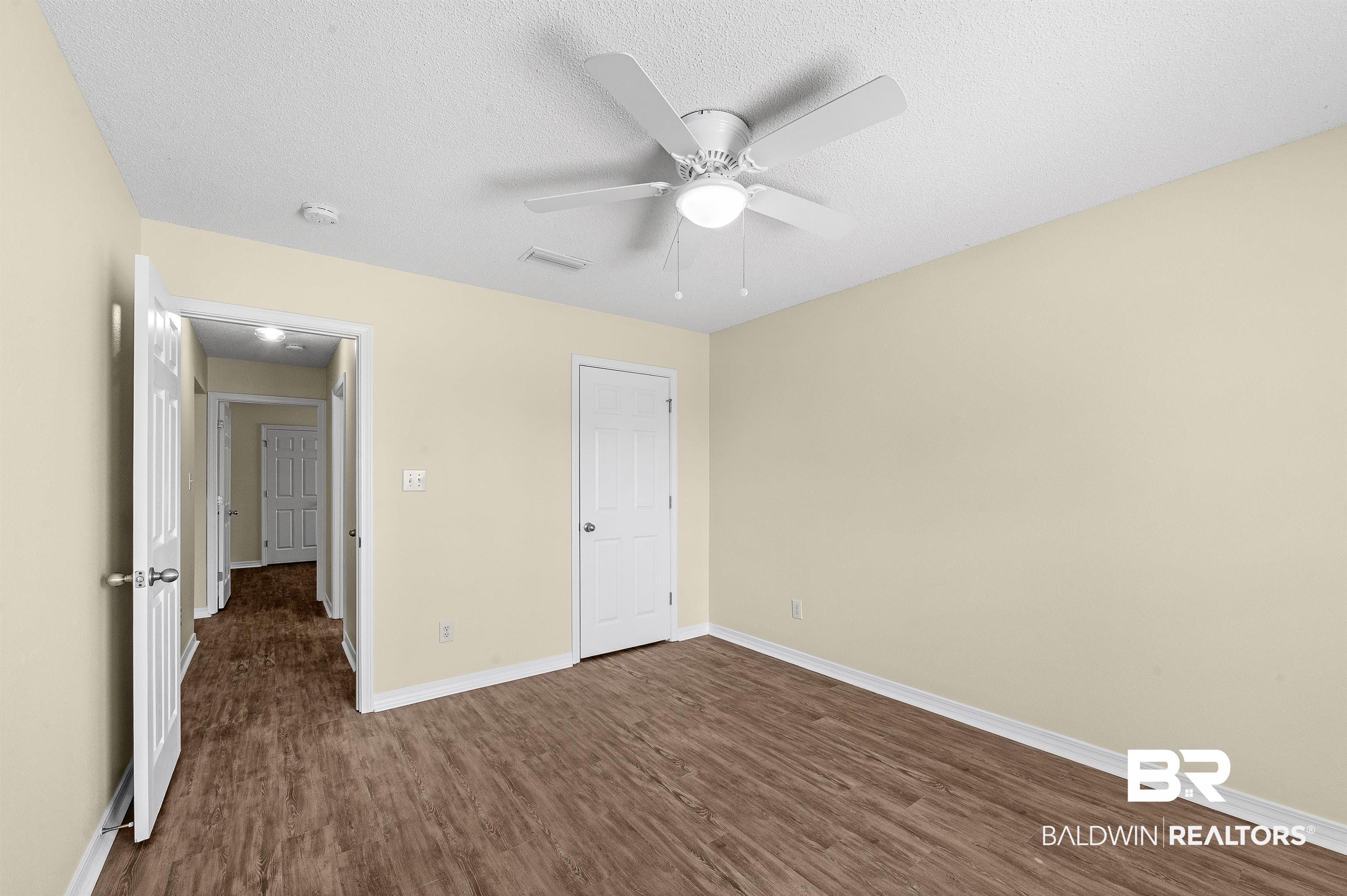 12443 Venice Boulevard Foley, AL 36535 - Photo 49 of 59 Unfurnished bedroom featuring dark wood-type flooring, ceiling fan, and a textured ceiling