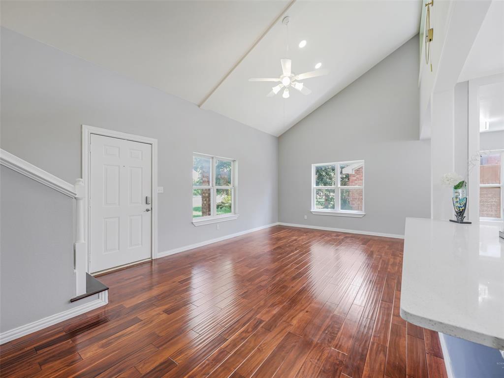 1716 East Parker Road Plano, TX 75074 - Photo 6 of 25 Spacious living area featuring vaulted ceilings, wood-finish flooring, and a ceiling fan with integrated lighting