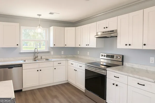 a kitchen with cabinets appliances a sink and a window