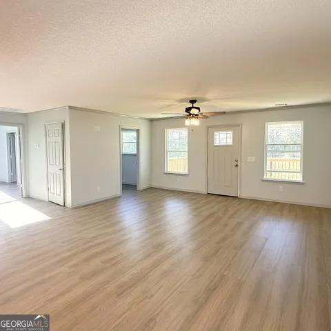 an empty room with wooden floor and windows