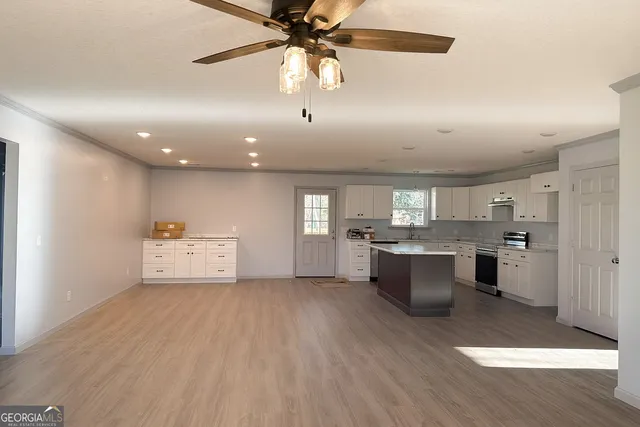 a large white kitchen with a large counter top appliances and cabinets