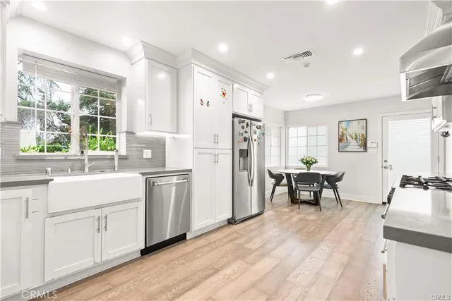 a kitchen with white cabinets and wooden floor