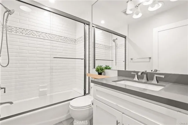 a bathroom with a granite countertop sink a toilet a mirror and shower