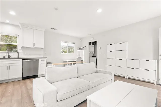 a kitchen with stainless steel appliances granite countertop white cabinets a sink a stove a microwave and wooden floors