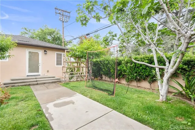 a view of a white house with a yard and sitting area