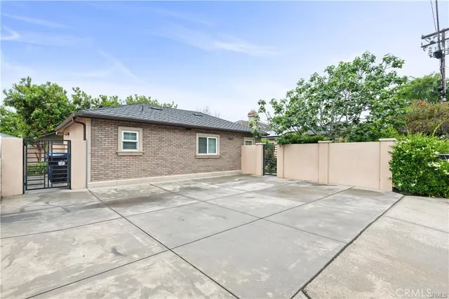 a view of a brick house with a big yard plants and large trees