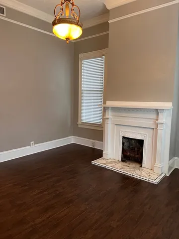 a view of a room with wooden floor a fireplace and a window