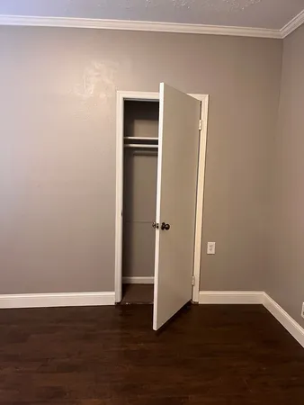 a view of an empty room with wooden floor and closet