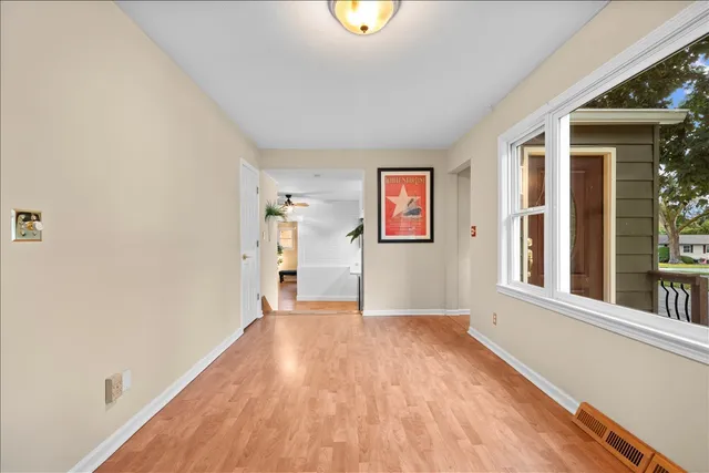 a view of an empty room with window and wooden floor