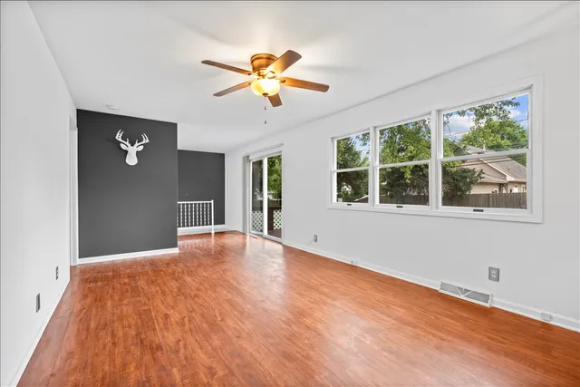 a view of empty room with wooden floor and fan