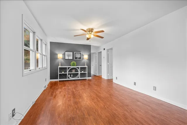 a view of a livingroom with lounge chair and a chandelier fan