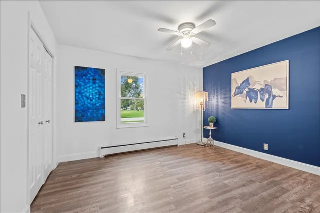 a view of empty room with wooden floor and fan