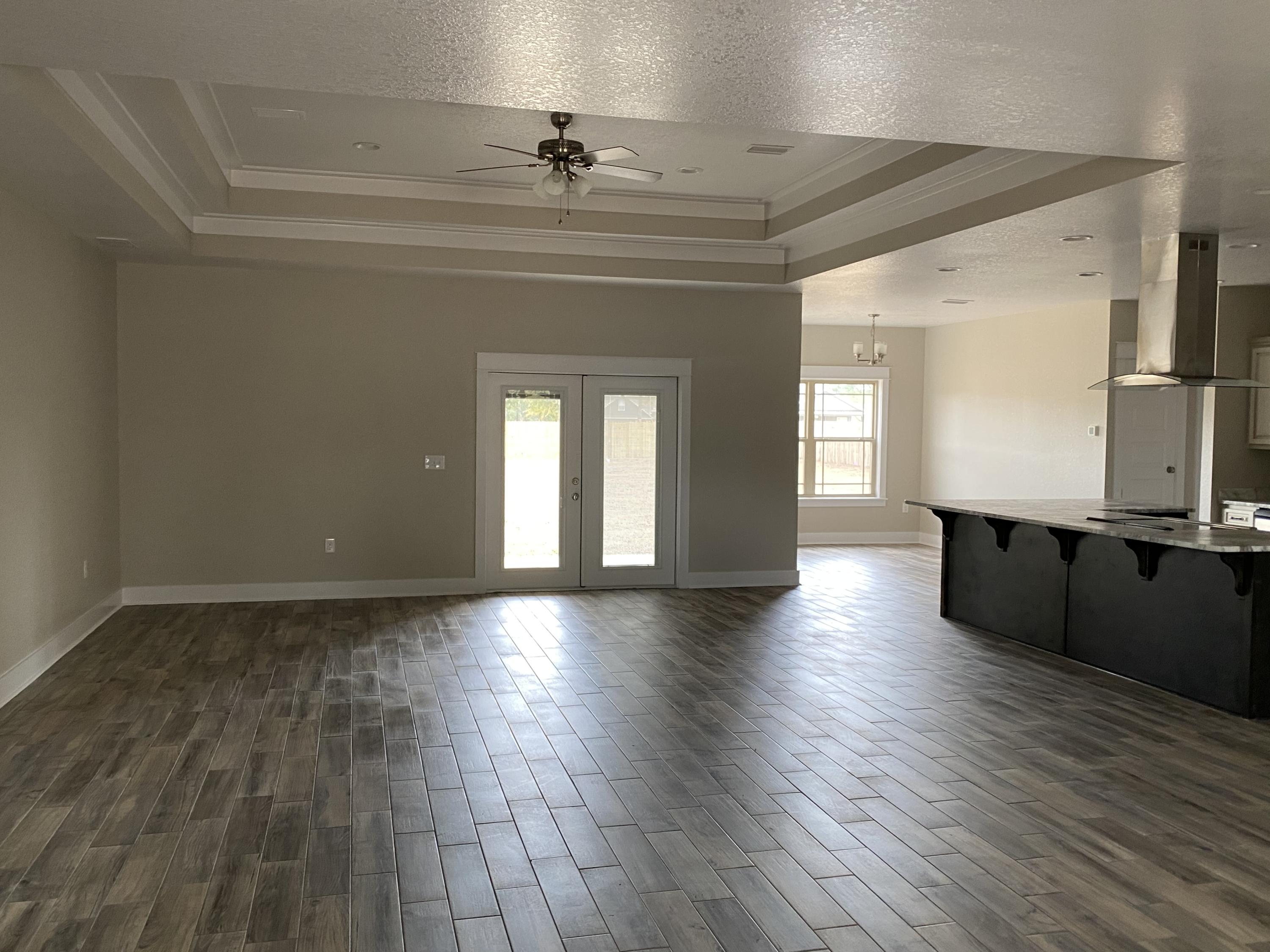 3958 Painter Branch Road Crestview, FL 32539 - Photo 7 of 15 a view of an empty room with wooden floor and a kitchen