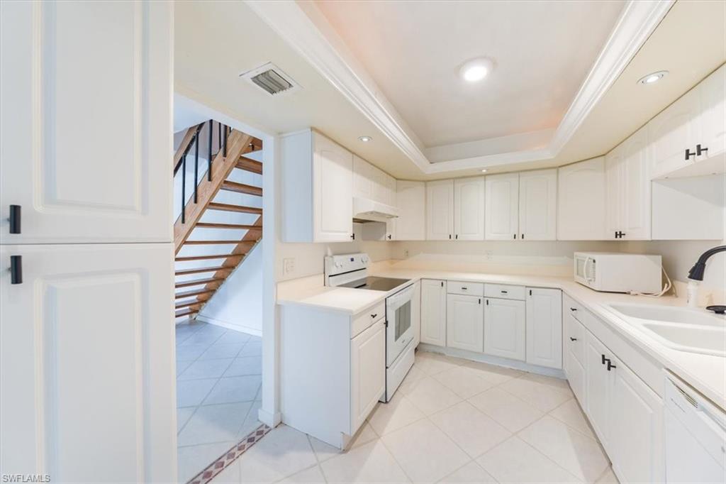 925 Palm View Drive, Unit E118 Naples, FL 34110 - Photo 11 of 26 a kitchen with white cabinets appliances and sink