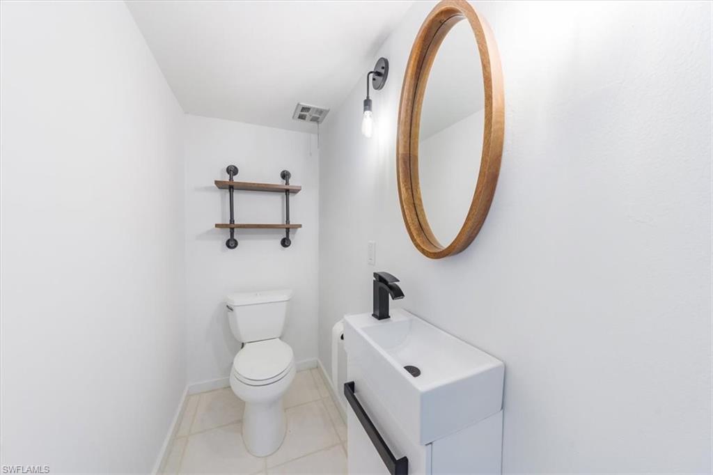 925 Palm View Drive, Unit E118 Naples, FL 34110 - Photo 14 of 26 a bathroom with a toilet sink and mirror