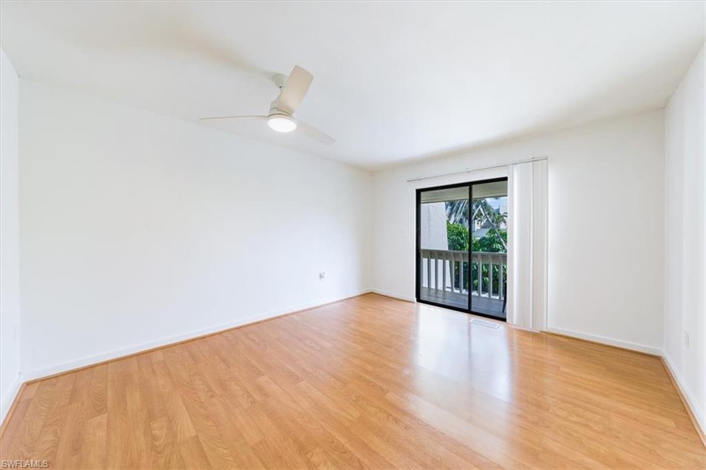 925 Palm View Drive, Unit E118 Naples, FL 34110 - Photo 18 of 26 a view of an empty room with wooden floor and a window