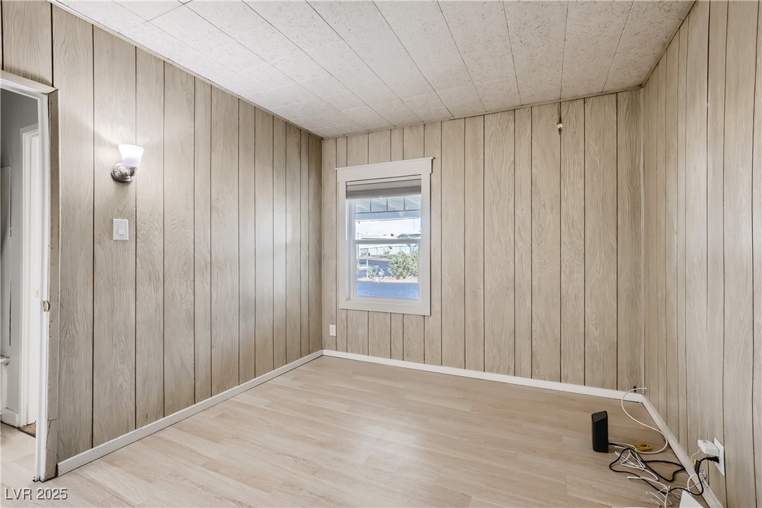103 West Victory Road Henderson, NV 89015 - Photo 22 of 28 Empty room with wood finished floors, wooden walls, and baseboards