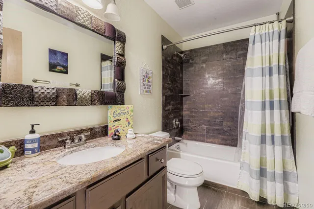 a bathroom with a granite countertop sink toilet and shower