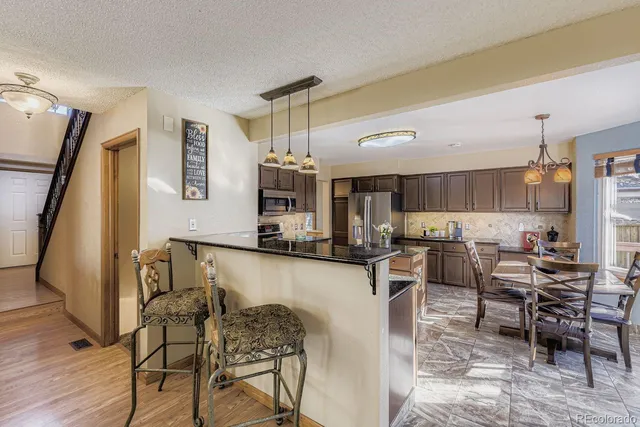a kitchen with stainless steel appliances kitchen island granite countertop a table chairs sink and cabinets