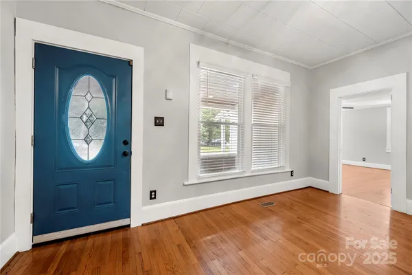 an empty room with window and hardwood floor