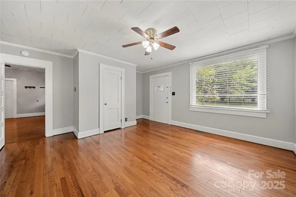 a view of an empty room with wooden floor and a window