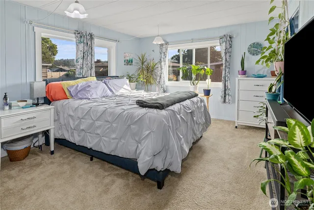 a bedroom with a bed and large windows