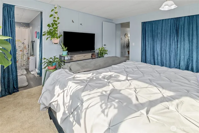 a bedroom with a bed and a flat tv screen on dresser