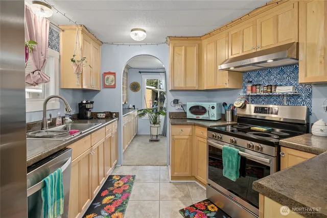 a kitchen with stainless steel appliances granite countertop a stove a sink and a microwave