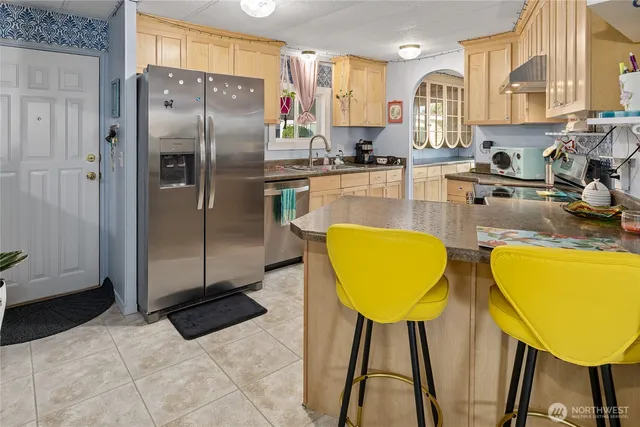 a kitchen with stainless steel appliances granite countertop a sink refrigerator and cabinets
