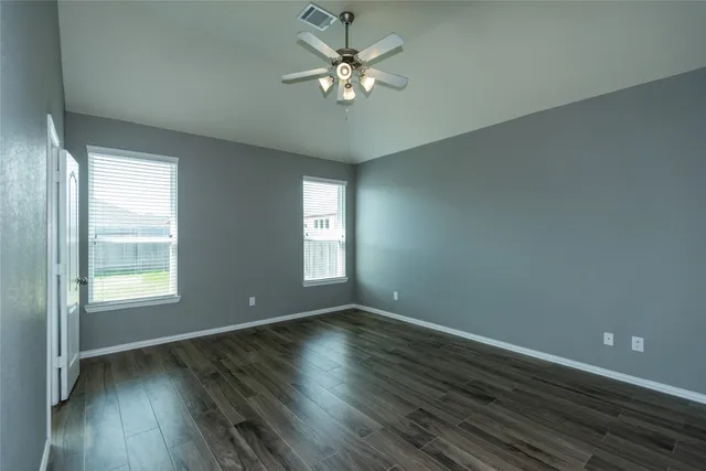 an empty room with wooden floor and windows