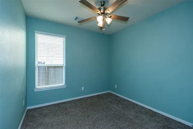 an empty room with a window and a fan