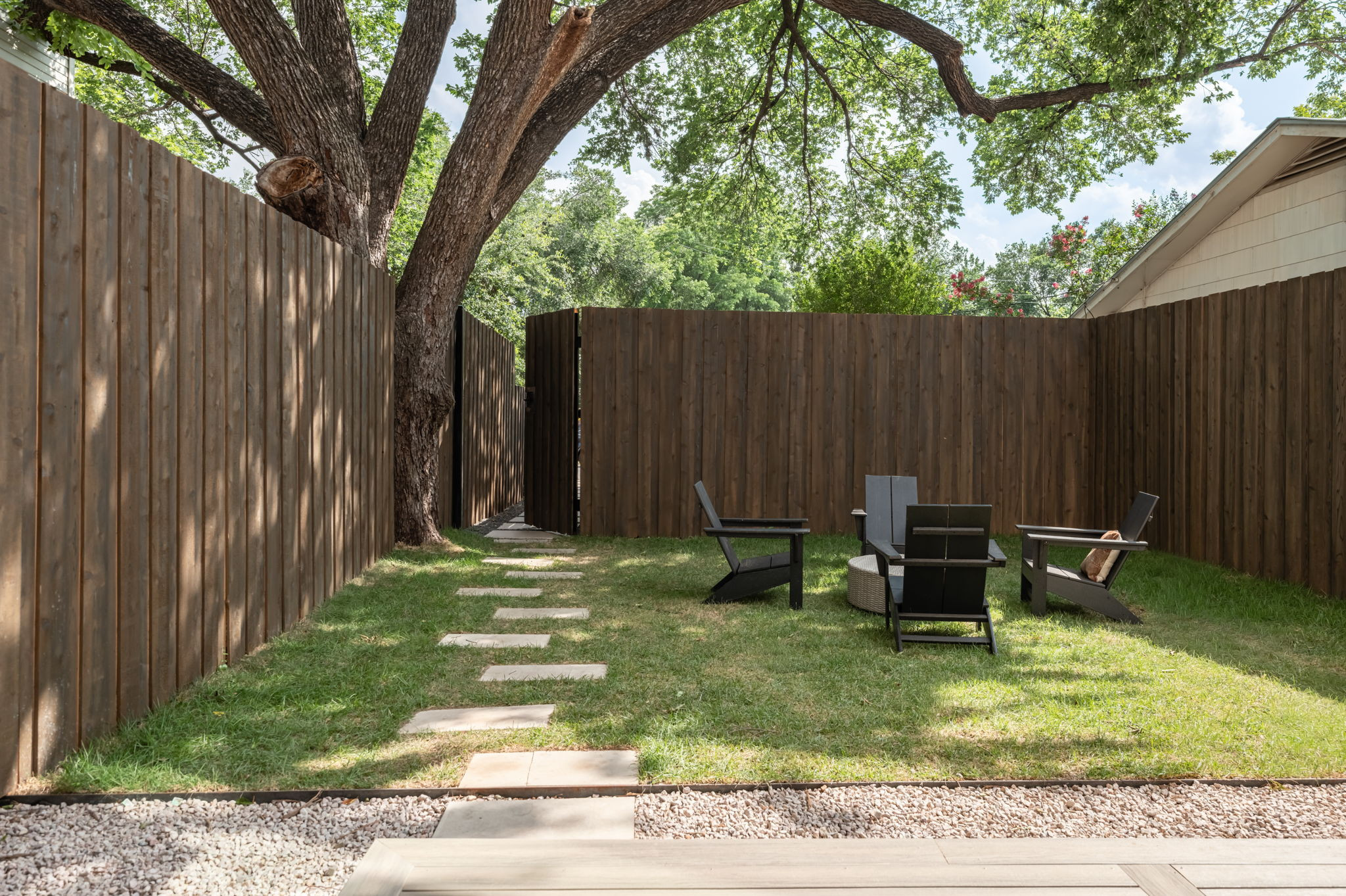 4713 Bolm Road Austin, TX 78702 - Photo 39 of 40 Expansive backyard featuring a manicured lawn, established mature tree, full privacy fencing, a stone paver pathway, and a gravel border