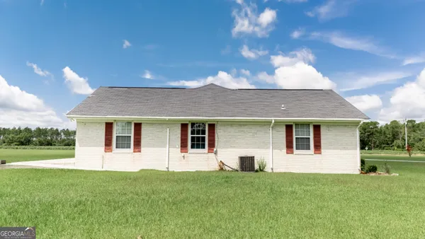 a view of an house with a big yard and large trees