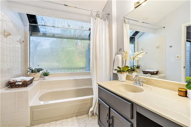 a bathroom with a granite countertop sink and a bathtub