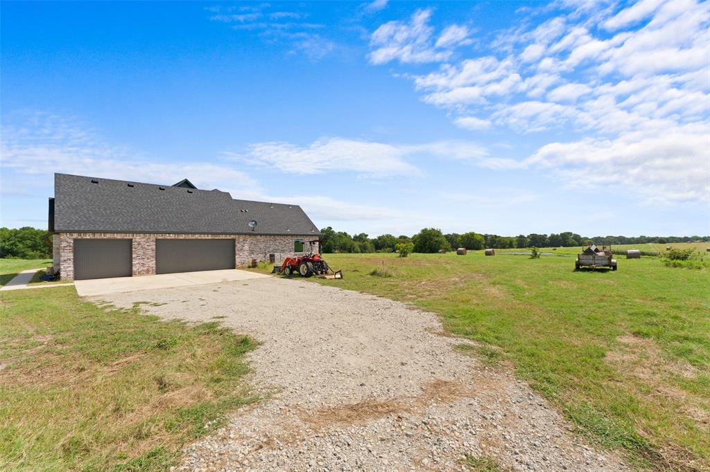 4411 Fm 751 Wills Point Wills Point, TX 75169 - Photo 36 of 40 Modern brick exterior featuring two garage doors, dark shingle roofing, and a gravel driveway