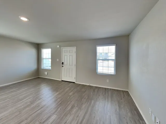 an empty room with wooden floor and windows