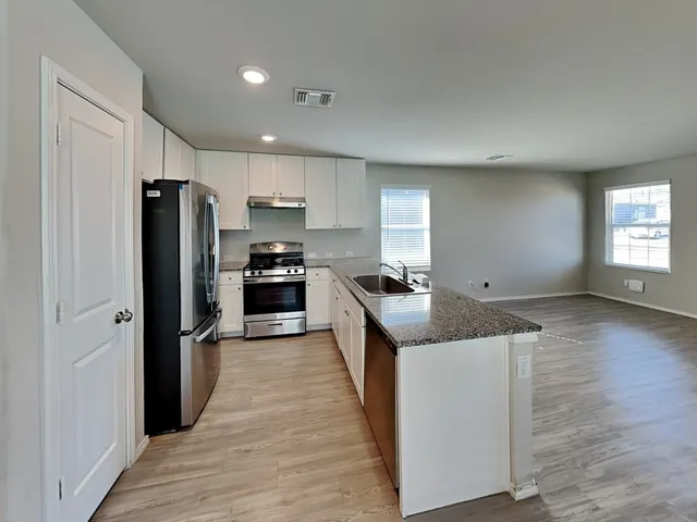 a kitchen with stainless steel appliances granite countertop a refrigerator a stove and a wooden floors