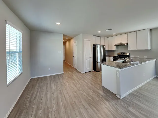 a kitchen with wooden floors white cabinets and stainless steel appliances