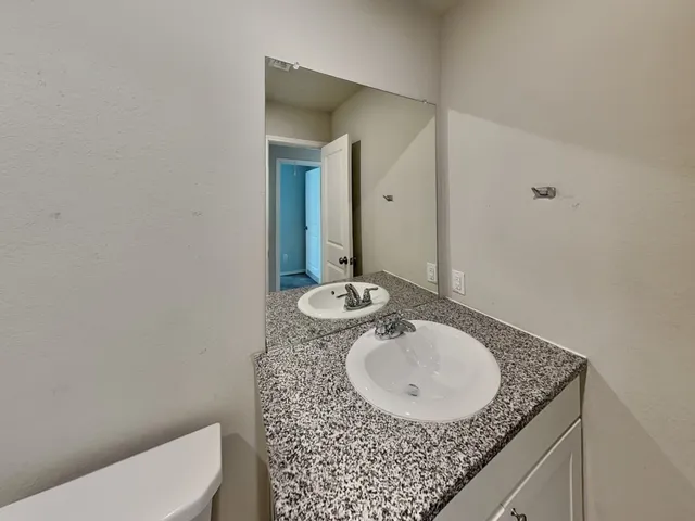 a bathroom with a granite countertop sink a mirror and a toilet
