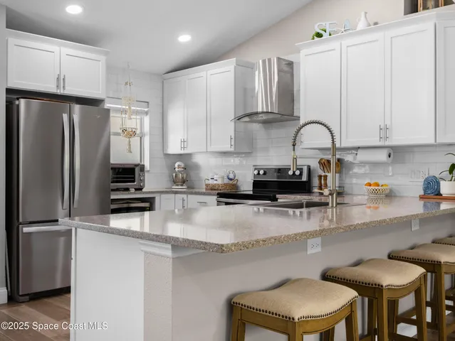 a kitchen with stainless steel appliances granite countertop a stove a sink a refrigerator and white cabinets