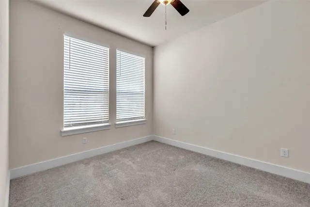 an empty room with a ceiling fan and window