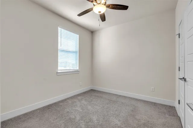 an empty room with ceiling fan and window
